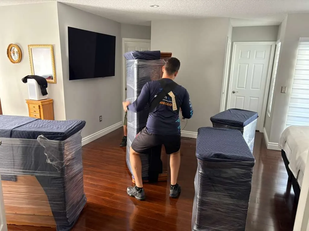 DY Moving mover with furniture wrapped in protective plastic and blankets