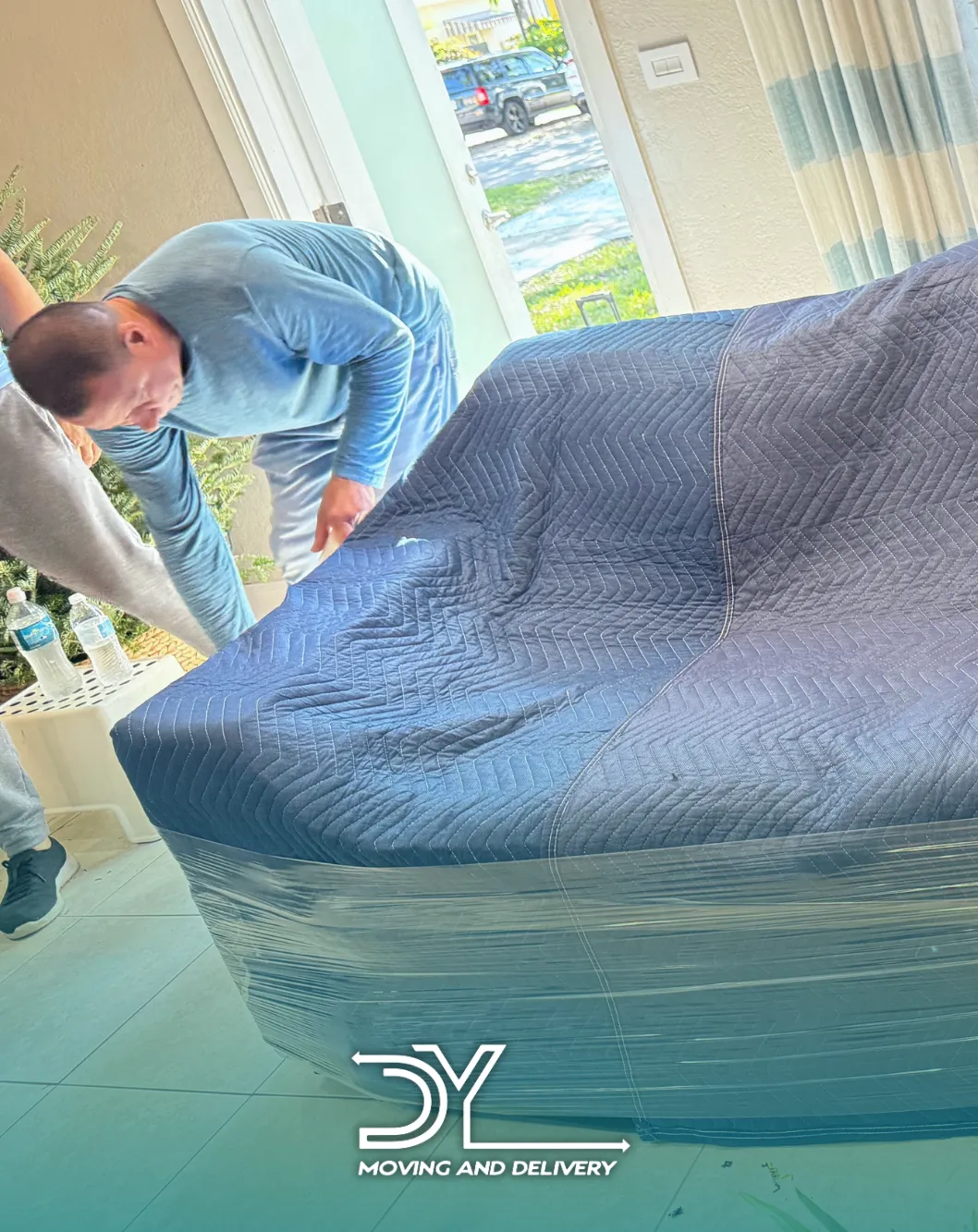 DY Moving crew member covering a sofa with a moving blanket